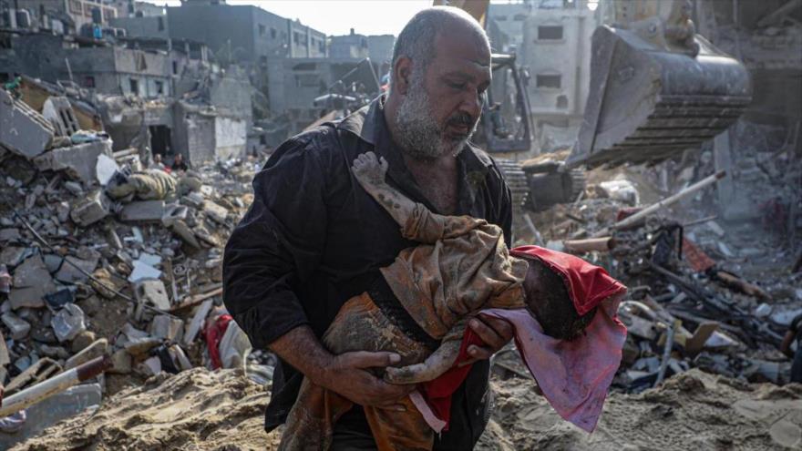 Un hombre recupera el cadáver de una niña de entre los escombros tras un bombardeo israelí en el campo de Yabalia, en el norte de Gaza. (Foto: EFE)