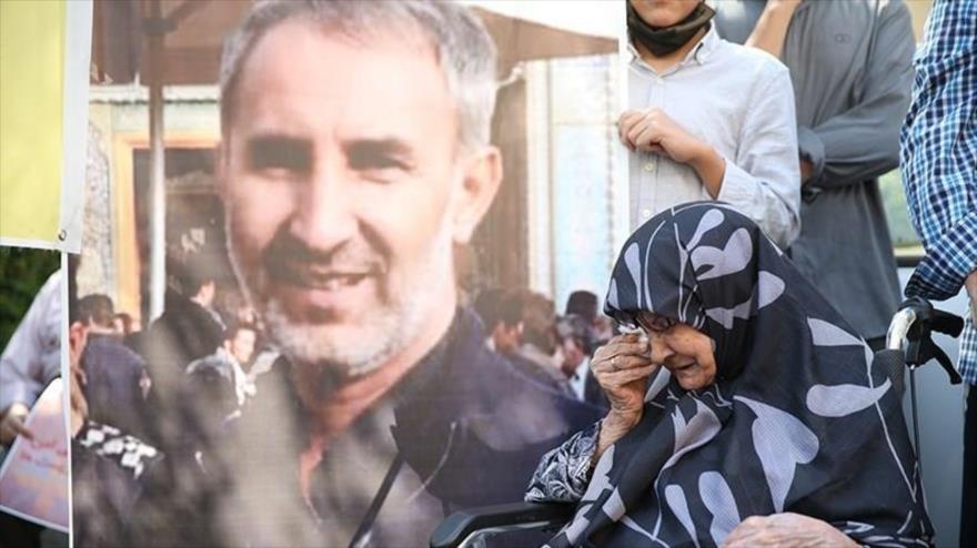 La madre del ciudadano iraní encarcelado en Suecia, Hamid Nuri, llora junto a la imagen de su hijo en una protesta frente a la embajada sueca, Teherán. (Foto: Tasnim)
