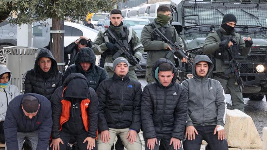 Soldados israelíes hacen guardia mientras musulmanes palestinos realizan la oración del mediodía del viernes en el barrio oriental de Al-Quds, el 2 de febrero de 2024. (Foto: AFP)