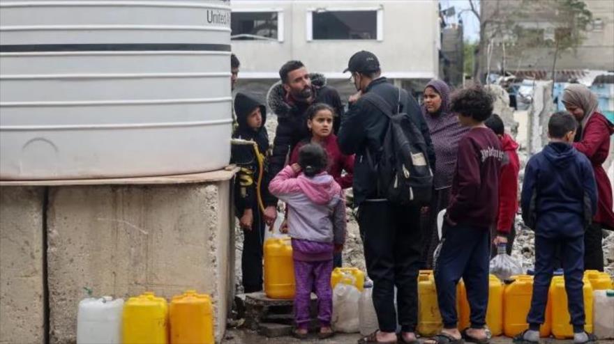 Familias palestinas desplazadas hacen cola para llenar jarras de plástico de un tanque de agua en Rafah, en el sur de la Franja de Gaza, el 28 de enero de 2024.