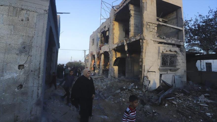 Palestinos caminan junto a un edificio residencial destruido en un ataque israelí en Rafah, sur de la Franja de Gaza, 11 de febrero de 2024. (Foto: AP)
