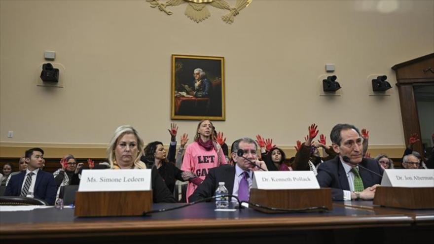 Activistas levantan sus manos manchadas de rojo en una sesión de la Cámara de Representantes de EE.UU., 14 de febrero de 2024.