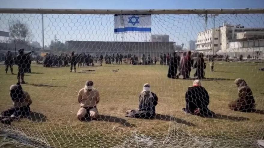Una captura de un vídeo parece mostrar a mujeres y hombres palestinos detenidos por el ejército israelí en el césped en un estadio.