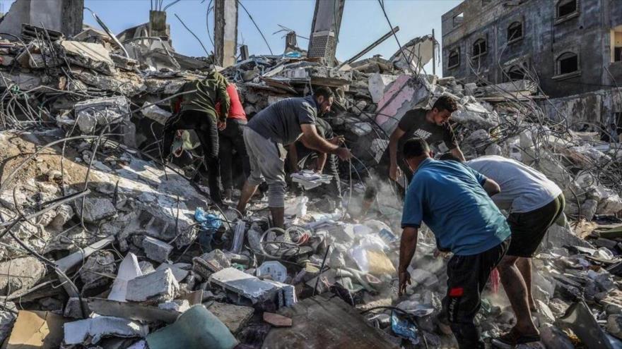 Un grupo de palestinos busca entre los escombros de un edificio destruido tras un bombardeo israelí contra Rafah, sur de Gaza.