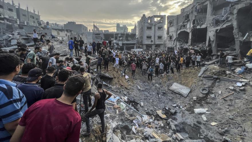Los palestinos entre las casas arruinadas por ataques de Israel en busca de los heridos.