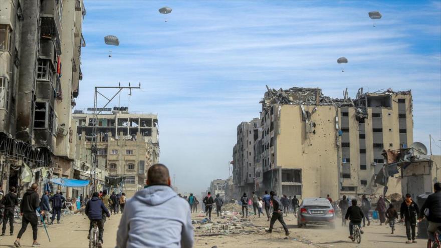 Palestinos persiguen cargas de ayuda humanitaria lanzadas desde el aire en la ciudad de Gaza, 1 de marzo de 2024. (Foto: AFP)