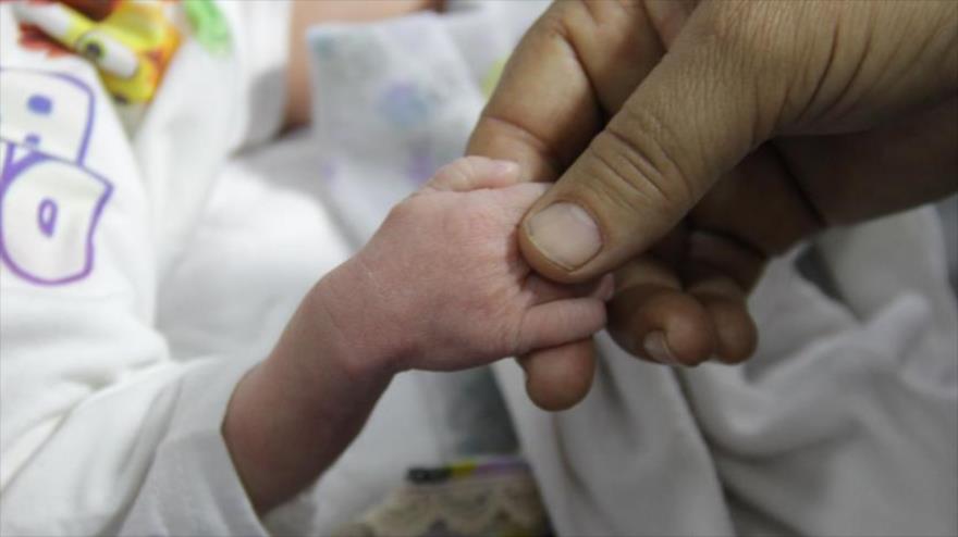 Un hombre sostiene la mano de un bebé hospitalizado debido a la desnutrición en un centro de salud en Gaza, 2 de marzo de 2024.