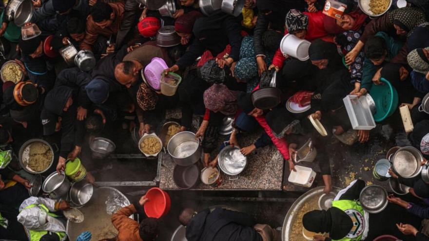 Los palestinos reciben alimentos donados en medio de los continuos ataques indiscriminados de Israel en Gaza. (Foto: Getty Images)