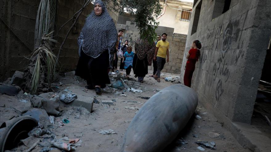 Los palestinos observan una bomba sin explotar lanzada por un avión de combate israelí F-16 en el barrio Rimal de la ciudad de Gaza, mayo de 2021. (Foto: Getty Images)