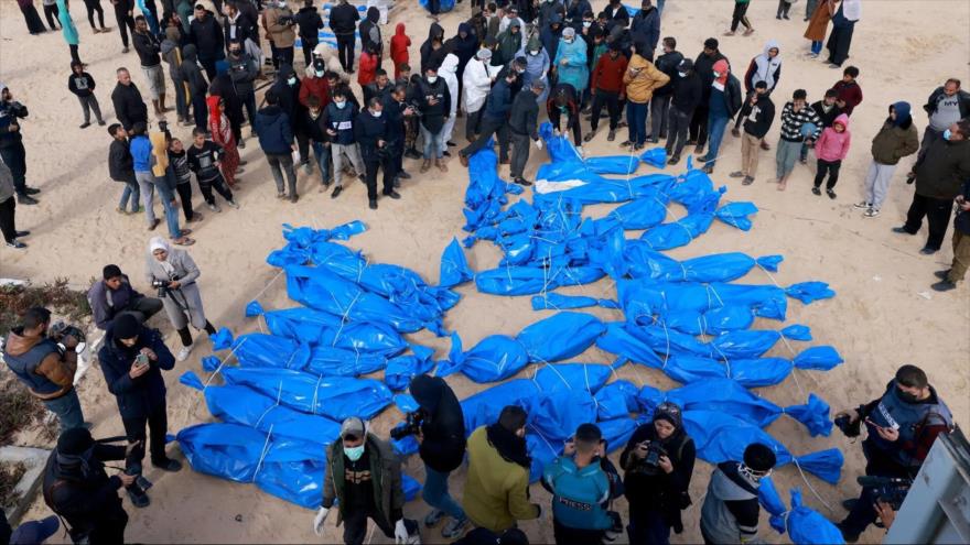 La gente observa a los trabajadores del Ministerio de Salud palestino enterrar los cuerpos de palestinos no identificados. (Foto: Getty Images)
