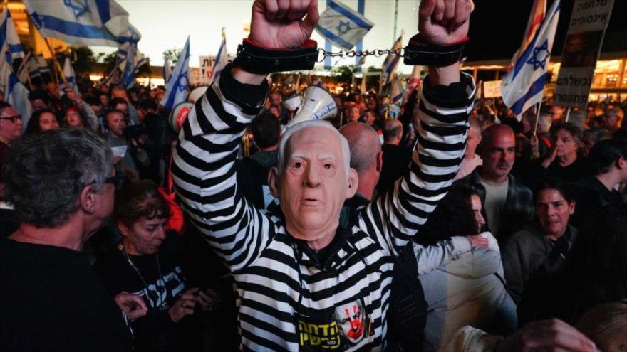 Una persona vestida de preso lleva una máscara que representa a Netanyahu, durante una manifestación contra el gabinete israelí en Tel Aviv. (Foto: Reuters)