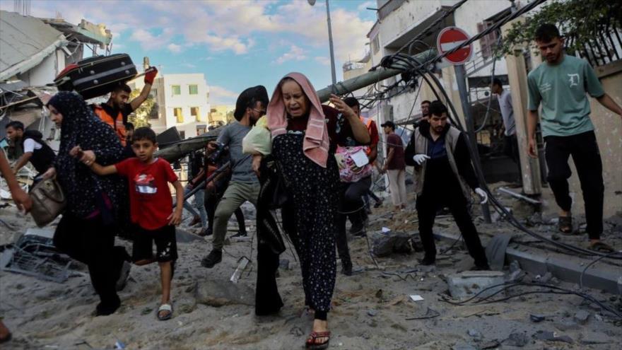 Las familias palestinas salen corriendo de sus hogares después de ataques aéreos israelíes contra su vecindario en Gaza, 17 de octubre de 2023. (Foto: AP)