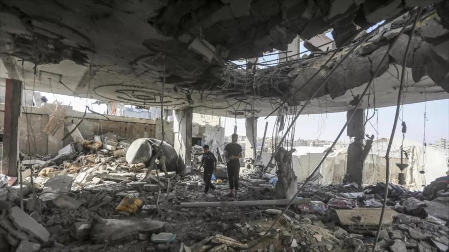 Dos jóvenes palestinos entre los escombros de un edificio destruido en los ataques israelíes en la Franja de Gaza.