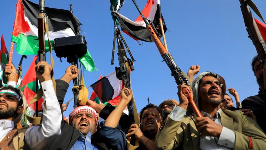La gente blande rifles y banderas palestinas durante una marcha para mostrar solidaridad con Gaza, en la capital yemení, Saná. (Foto: AFP)