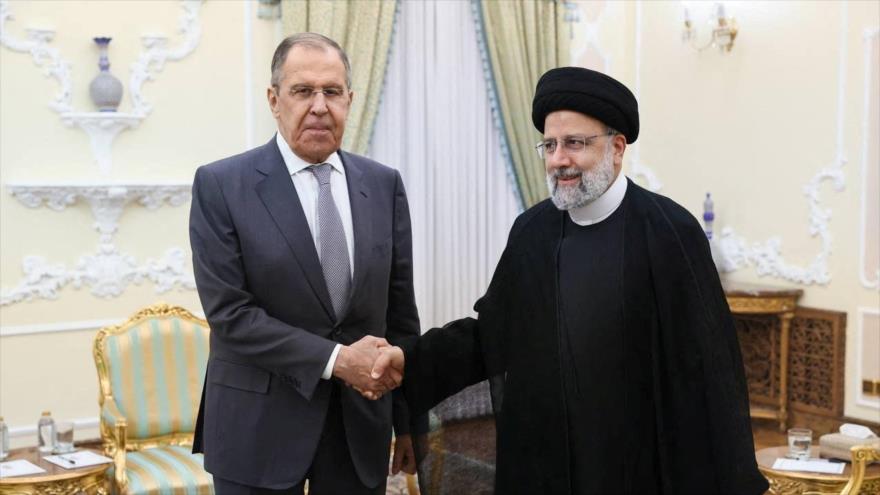 El canciller ruso, Serguéi Lavrov (izda.), le da la mano al difunto presidente iraní, Ebrahim Raisi, durante una reunión en Teherán, 23 de octubre de 2023. 