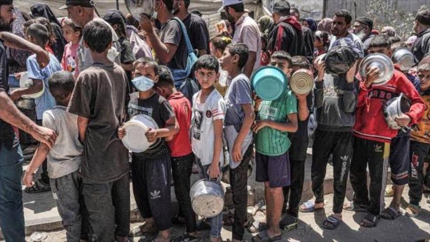 Los niños gazatíes entán en la cola para recibir las ayudas humanitarias.