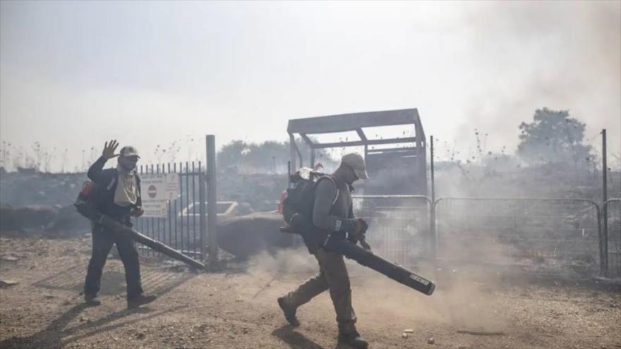 Bomberos israelíes realizan trabajos de extinción después de un incendio causado por el impacto de misiles Hezbolá en el norte de la Palestina ocupada.