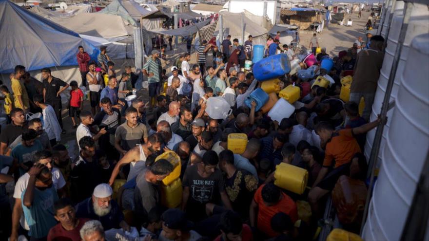 Palestinos desplazados por el bombardeo israelí hacen cola para conseguir agua en un campamento improvisado en Jan Yunes. (Foto: AP)
