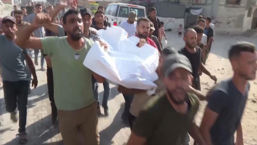 Palestinos llevan cádaveres encontrados en el barrio Tal al-Hawa, 12 de julio de 2024.