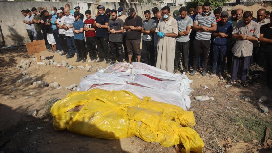 Palestinos rezan junto a los cuerpos de las víctimas de los ataques israelíes en el oeste de la ciudad de Gaza, 12 de julio de 2024.