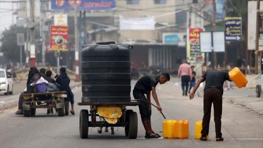 Varias personas llenan contenedores de plástico con agua potable en Rafah, en el sur de la Franja de Gaza, 23 de octubre de 2023.