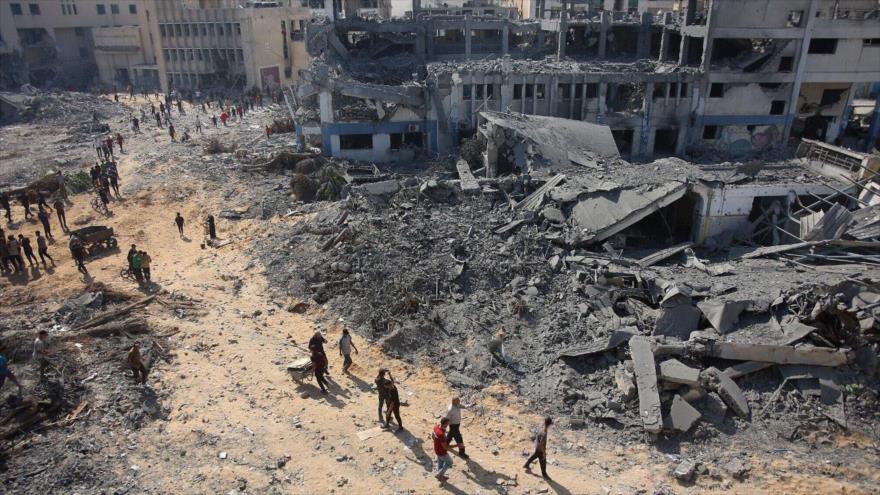 La gente camina sobre los escombros en el complejo de edificios dañado de la UNRWA en el oeste de la ciudad de Gaza, 12 de julio de 2024. (Foto: AFP)