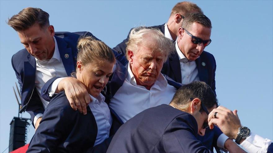 El expresidente de EE.UU., Donald Trump, rodeado por las fuerzas de seguridad tras el atentado fallido a su contra durante un mitin electoral, 13 de julio de 2024.