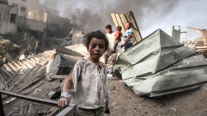 Una niña palestina ensangrentada de pie entre las ruinas tras un bombardeo israelí en Gaza, 25 de octubre de 2023. (Foto: AA)