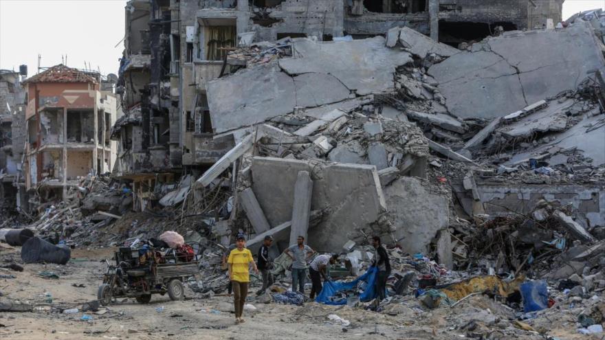 Varios hombres en Jan Yunis, Gaza, junto a las ruinas de un edificio destruido en un bombardeo de Israel. (Foto: EP)