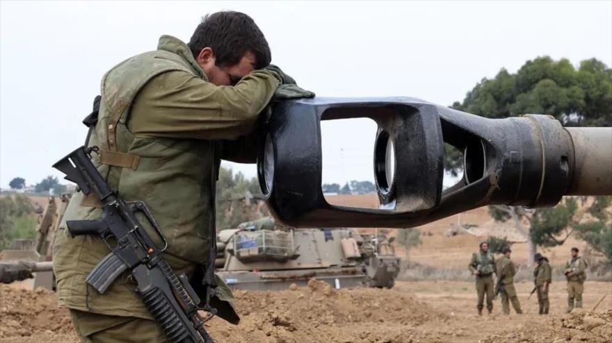 Un soldado israelí apoya su cabeza en el cañón de artillería de un vehículo blindado mientras los soldados israelíes toman posiciones cerca de la frontera con Gaza, 9 de octubre de 2023. (Foto: AFP)