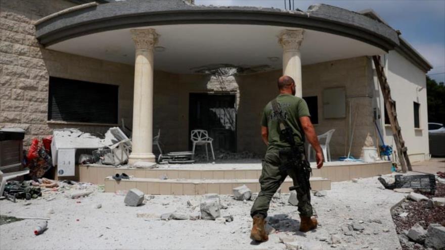 Un israelí camina cerca de un edificio dañado por el impacto directo de un ataque de Hezbolá, en el norte de los territorios ocupados, 25 de agosto de 2024. (Foto: Reuters)