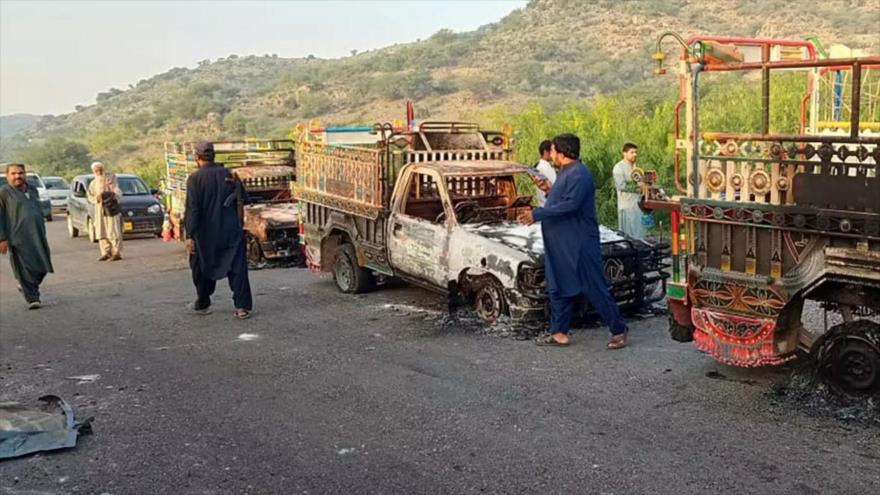 Gente mira vehículos quemados, incendiados por hombres armados tras matar a pasajeros, en Baluchistán en suroeste de Pakistán, 26 de agosto de 2024.