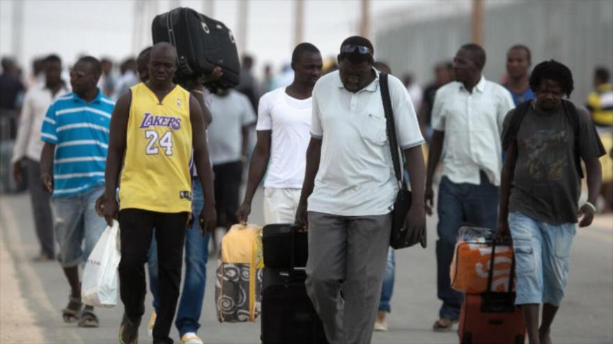 Migrantes africanos llevan sus pertenencias tras ser liberados del centro de detención de Holot, en el desierto del Néguev, en los territorios ocupados por Israel. (Foto: AFP)
