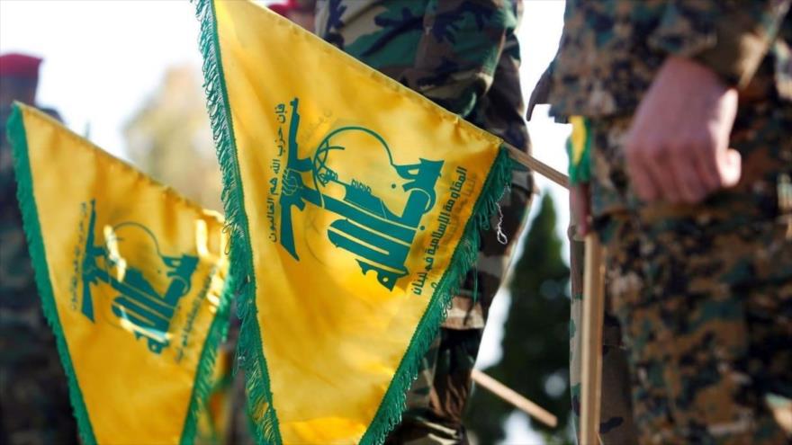 Combatientes de Hezbolá sosteniendo banderas del movimiento libanés.