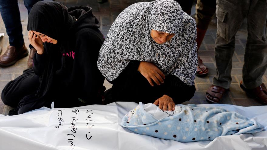 Dos mujeres palestinas lloran delante del cuerpo de un bebé que murió en un bombardeo israelí contra Gaza, 12 de diciembre de 2023. (Foto: Reuters)