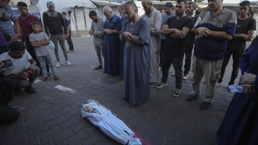 Dolientes rezan sobre el cuerpo de un niño palestino, fallecido en el bombardeo israelí sobre la Franja de Gaza, ante la morgue de un hospital, en Deir al-Balah, 9 de octubre de 2024. (Foto: AP)
