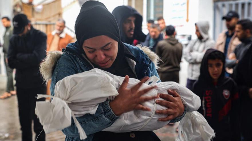 Una mujer llora mientras lleva en brazos el cuerpo envuelto en una sábana de un niño que murió tras los ataques israelíes en Rafah (Gaza), 6 de mayo de 2024. (Foto: AFP).