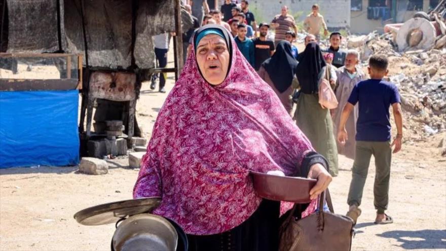 Mujer lleva ollas y recipientes mientras abandona el campo de refugiados de Yabalia, el 9 de octubre de 2024 (Foto AFP)