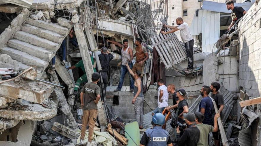 La gente se reúne afuera de un edificio derrumbado en un bombardeo israelí en el distrito de Saftawi en Yabalia, en el norte de Gaza, 15 de octubre de 2024.