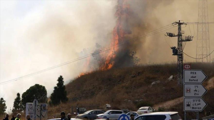 Las fuerzas de seguridad israelíes y los servicios de emergencia en el lugar de un incendio en una colina tras un ataque de Hezbolá. (Foto: AFP)