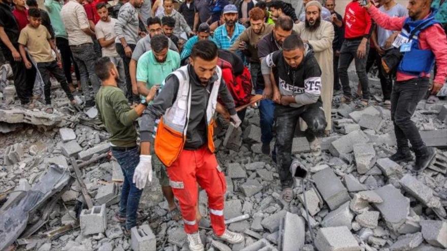 Miembros de la Defensa Civil Palestina y otros voluntarios llevan el cuerpo de una víctima que fue rescatada de los escombros tras un bombardeo israelí en Gaza, 26 de octubre de 2024. (Foto: AFP)