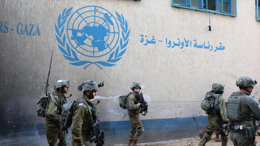 Soldados israelíes caminan frente a la sede de UNRWA en Gaza, 8 de febrero de 2024. (Foto: AFP)