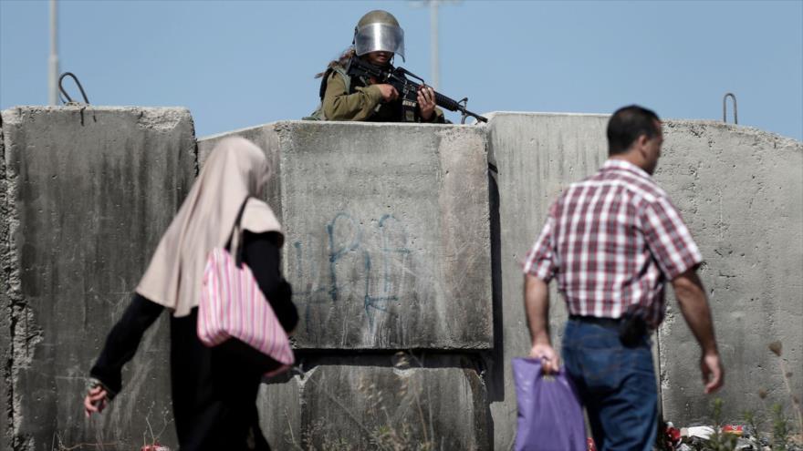 Una militar israelí vigila desde un muro el paso de los palestinos en una zona en la ocupada Cisjordania.