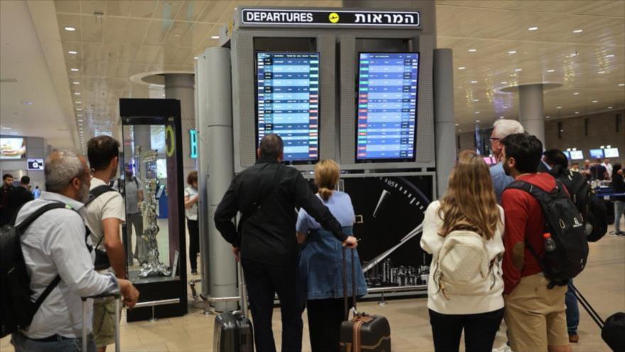 Pasajeros miran un tablero de salidas en el aeropuerto Ben Gurion, cerca de Tel Aviv, mientras los vuelos se cancelan y retrasan.