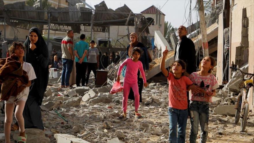 Gazatíes en medio de los escombros que dejan los ataques israelíes.