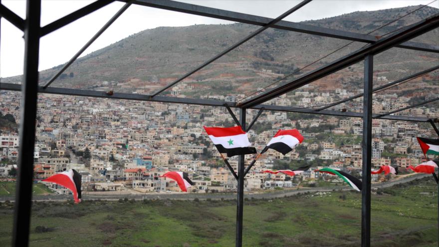 Banderas de Siria y Palestina en la ciudad siria de Ain Al-Tineh, al otro lado de altos del Golán ocupados por Israel, 26 de marzo de 2019. (Foto: AFP)