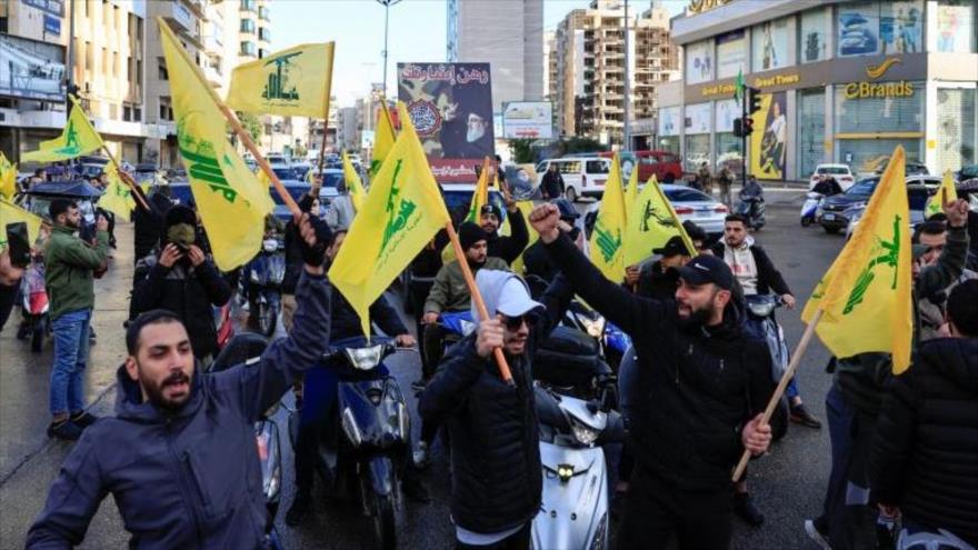 Ciudadanos libaneses sostienen banderas de Hezbolá a la entrada de los suburbios del sur de Beirut, 27 de noviembre de 2024. (Foto: Reuters)