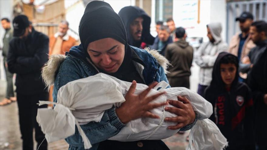 Una mujer llora mientras lleva el cuerpo envuelto en una manta de un niño muerto tras los ataques israelíes nocturnos en Rafah, en el sur de Gaza, 6 de mayo de 2024. (Foto: AFP)