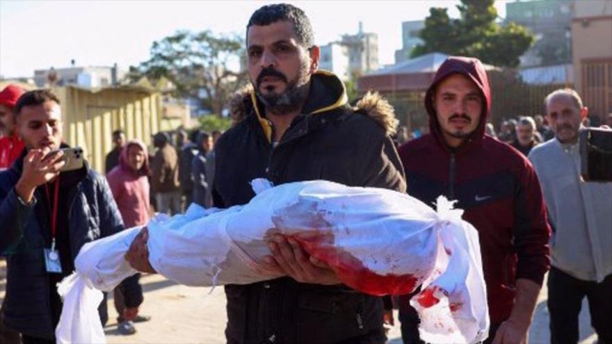 Un hombre carga a una de las víctimas de ataques israelíes contra una escuela de la ONU en Jan Yunis, sur de Gaza, 16 de diciembre de 2024. (Foto: AFP)