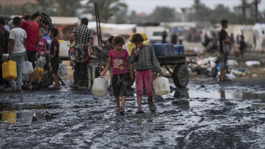 Palestinos se reúnen para llenar jarras de agua cerca de una de las pocas plantas desalinizadoras en funcionamiento de la Franja de Gaza en Deir al-Balah, 20 de junio de 2024. (Foto: AP)
